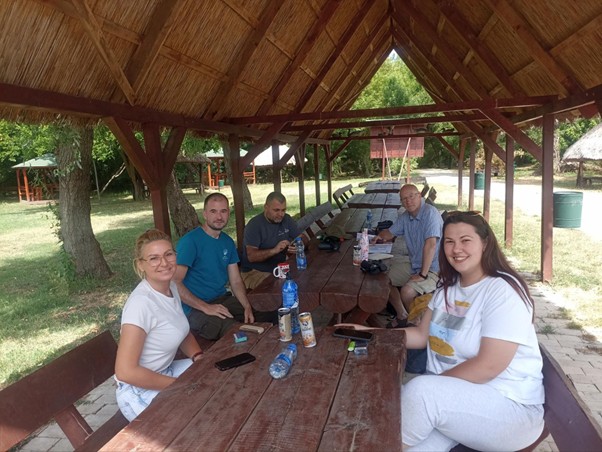 Group of 5 people sitting around a picnic table