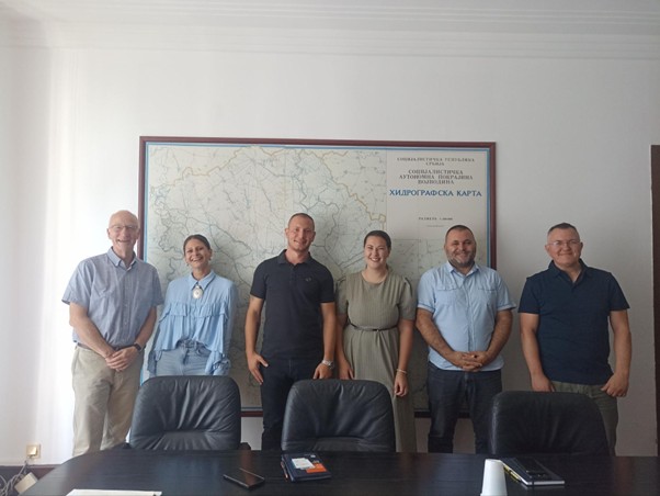 Group of 6 people posing behind a desk for a group photo